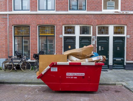 A covered skip outside a home in Osterley with recycling signage